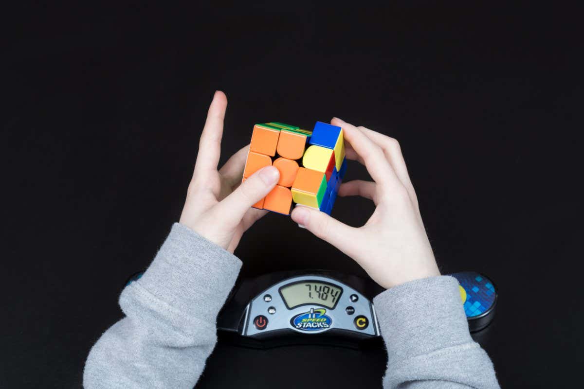 Dnipro, Ukraine - May 11, 2020: Boy solving Rubik?s cube using cube timer. Concept of speedcubing. Child hands with Rubik?s cube on black background. Top view. Closeup shot.; Shutterstock ID 1914173662; purchase_order: -; job: -; client: -; other: -