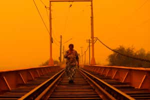 TOPSHOT - A woman walks on a bridge during the fires in Renaico, Araucania region, Chile on February 4, 2023. - At least 23 people have died in hundreds of forest fires whipped up amid a blistering heat wave in south central Chile, a senior government official said Saturday night. (Photo by JAVIER TORRES / AFP) (Photo by JAVIER TORRES/AFP via Getty Images)